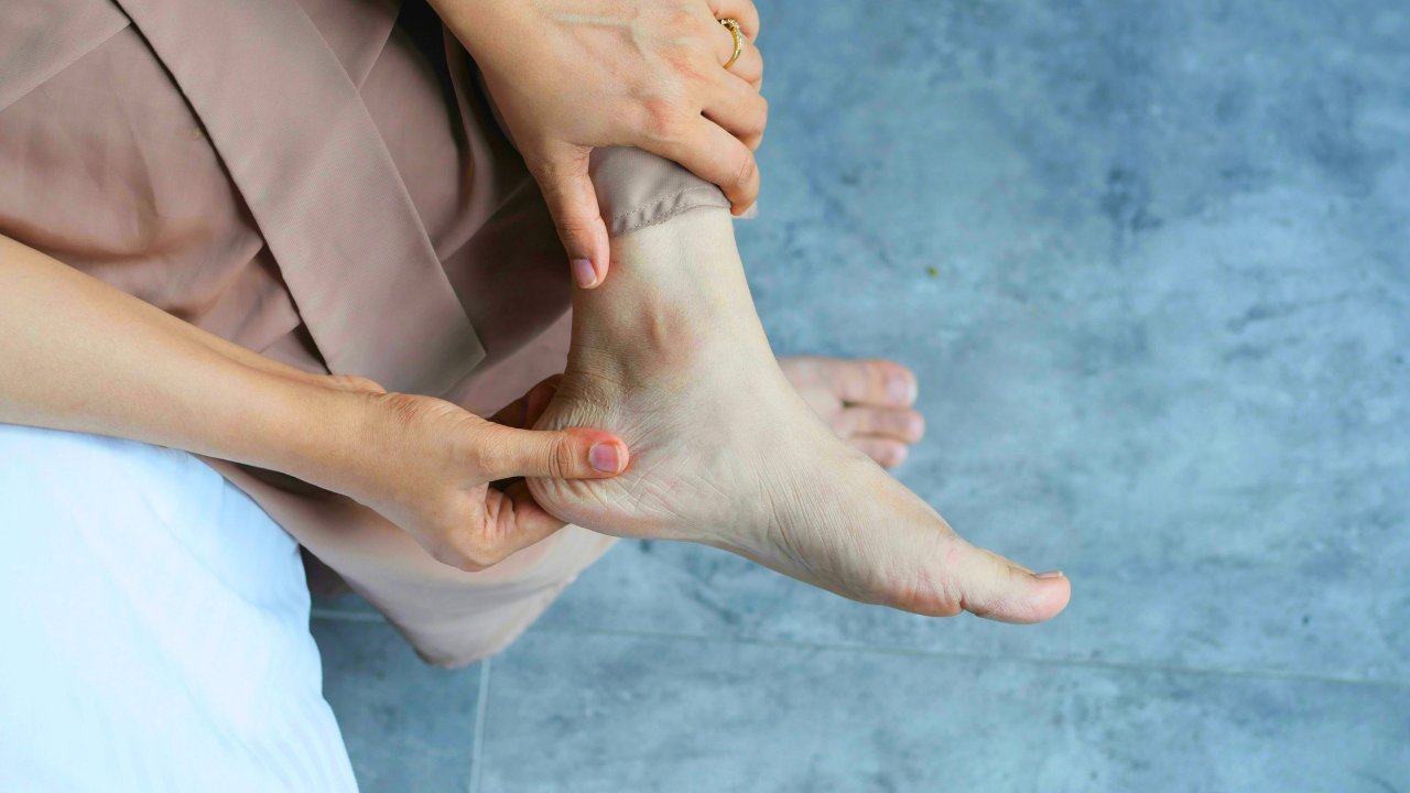 Patient holding her bare foot and ankle while seated